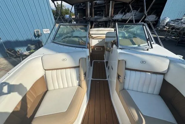 Slide: The Image of 2015 Cobalt 26SD boat interior with white and tan seating, docked near a blue building. - 22