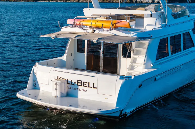 Slide: The Image of 2001 Navigator 61' Pilothouse yacht on water, featuring a spacious deck and kayaks. - 18
