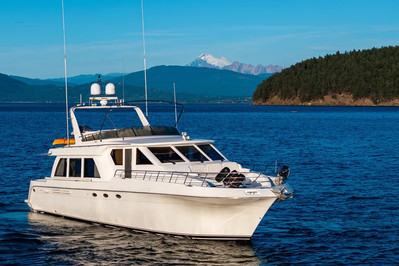 Slide: The Image of 2001 Navigator 61' Pilothouse yacht cruising on a scenic blue lake with mountainous backdrop. - 24