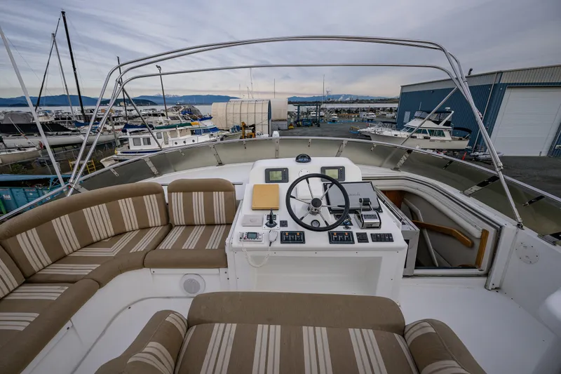 Slide: The Image of 2001 Navigator 61' Pilothouse yacht helm with striped seating, docked at marina. - 74