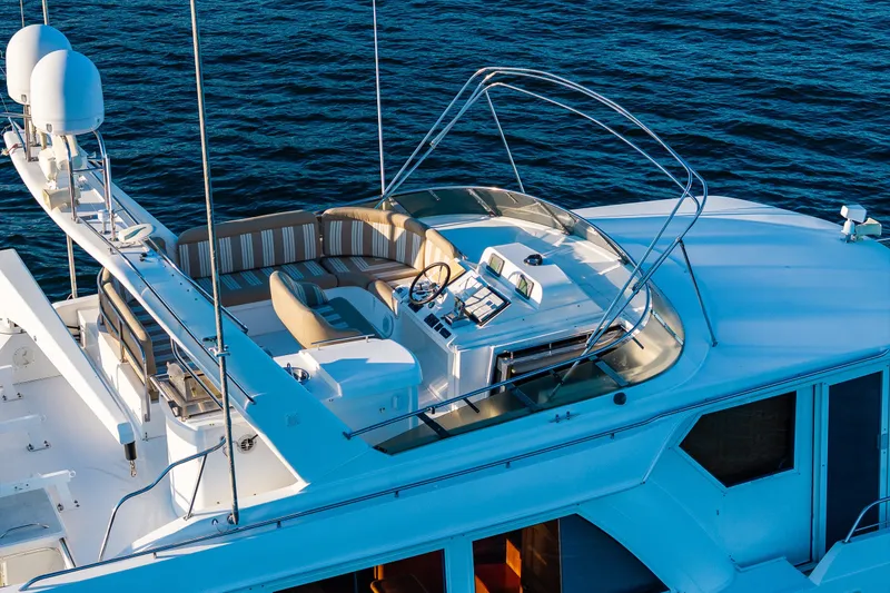 Slide: The Image of 2001 Navigator 61' Pilothouse yacht with spacious upper deck and seating, cruising on water. - 16