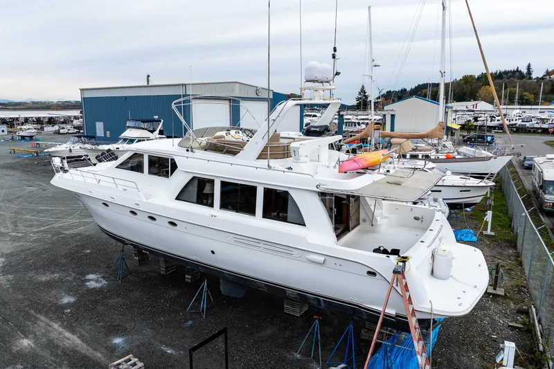 Slide: The Image of 2001 Navigator 61' Pilothouse yacht on dry dock, surrounded by other boats and marina buildings. - 45