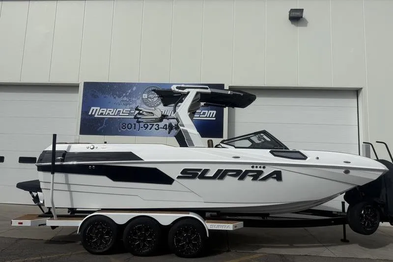 The Image of 2025 Supra SE 575 boat on trailer, displayed outside a marine dealership. - 1