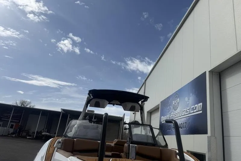Slide: The Image of 2025 Supra SE 575 boat outside a marine products warehouse under a clear sky. - 5