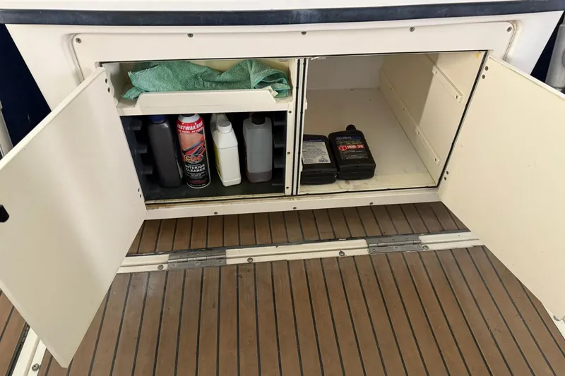Slide: The Image of Open storage compartment on a 2000 Boston Whaler 28 Outrage, containing cleaning supplies and oil. - 19