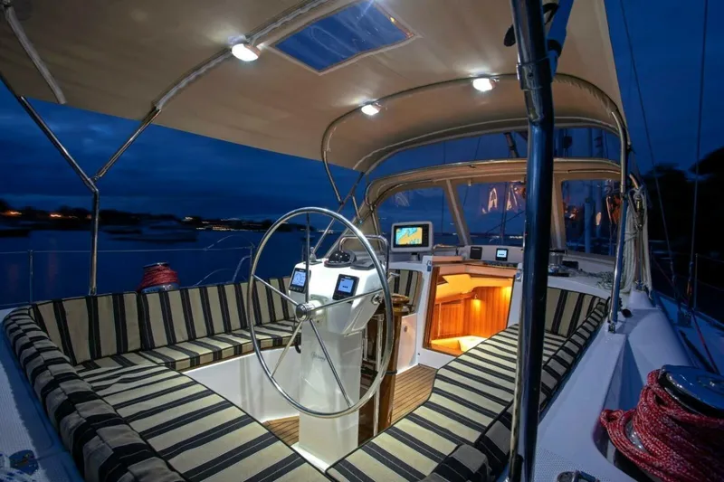 Slide: The Image of Luxurious 2025 Hylas H48 yacht cockpit at night, featuring striped seating and illuminated navigation. - 11