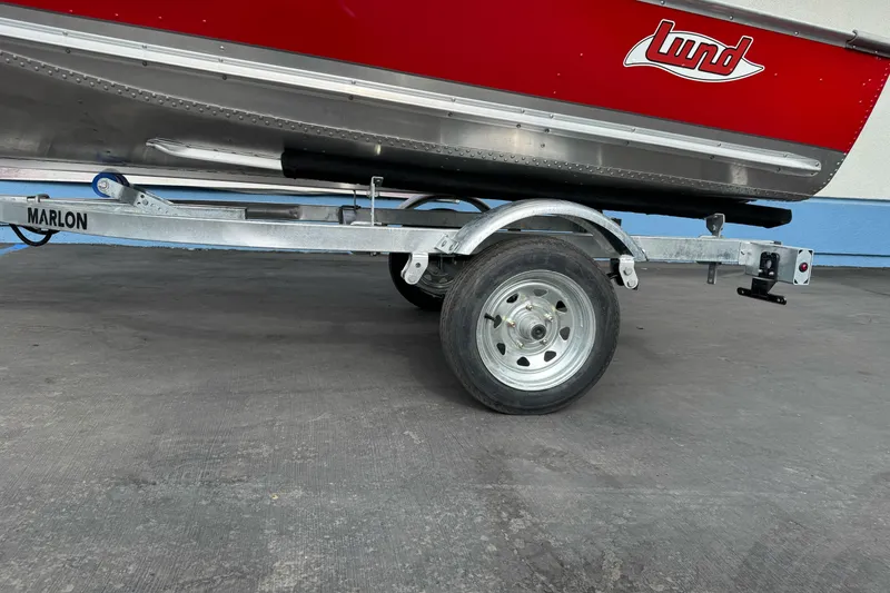Slide: The Image of 2026 Lund WC 12 boat on Marlon trailer, red exterior, parked on concrete surface. - 2