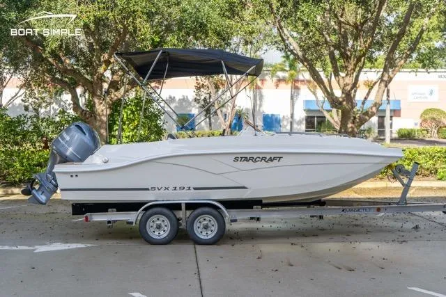 Slide: The Image of 2021 Starcraft SVX 191 OB boat on trailer, parked outdoors with trees in background. - 3
