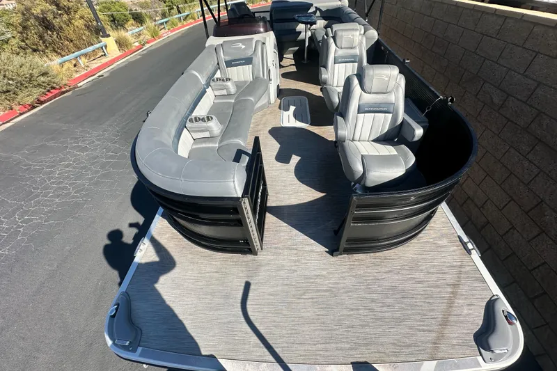 Slide: The Image of 2022 Bennington LX 24 L-Bench pontoon boat interior with gray seating and steering console. - 10