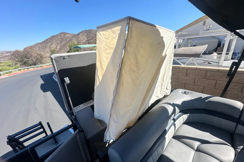 Slide: The Image of 2022 Bennington LX 24 L-Bench boat with privacy enclosure, scenic mountain backdrop. - 17