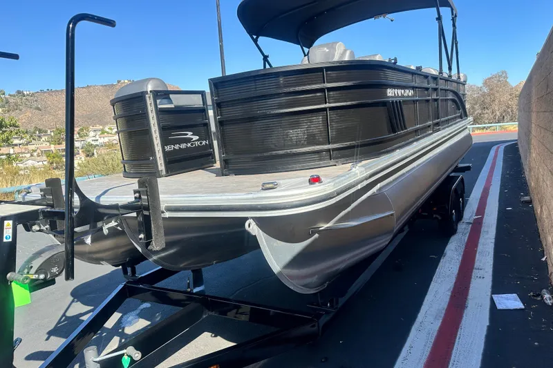 Slide: The Image of 2022 Bennington LX 24 L-Bench pontoon boat on trailer, parked outdoors. - 3