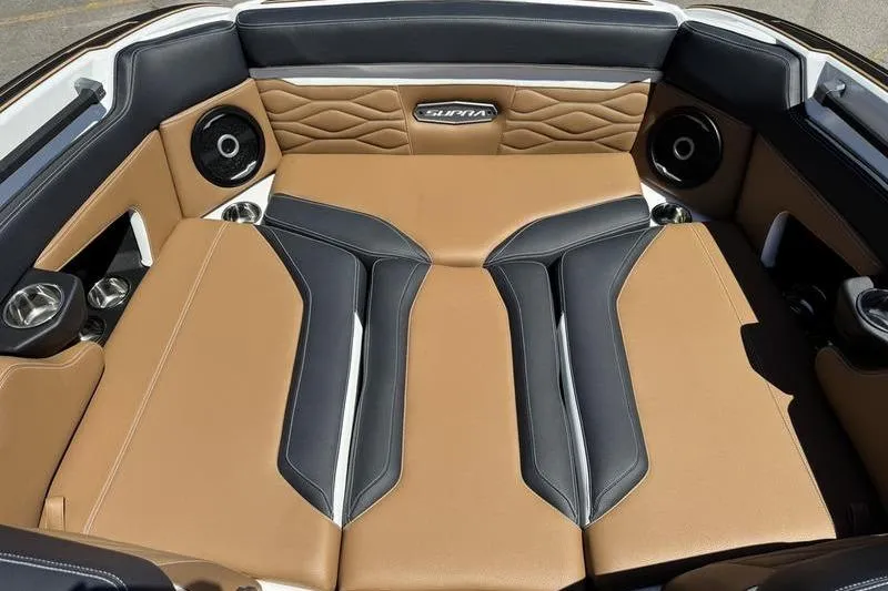 Slide: The Image of 2025 Supra SE 575 boat interior with tan and black leather seating, featuring speakers and cup holders. - 5