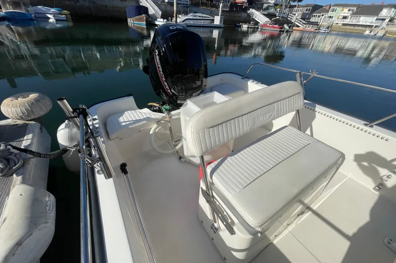 Slide: The Image of 2006 Boston Whaler 170 Montauk boat interior with seating and motor, docked in a marina. - 13
