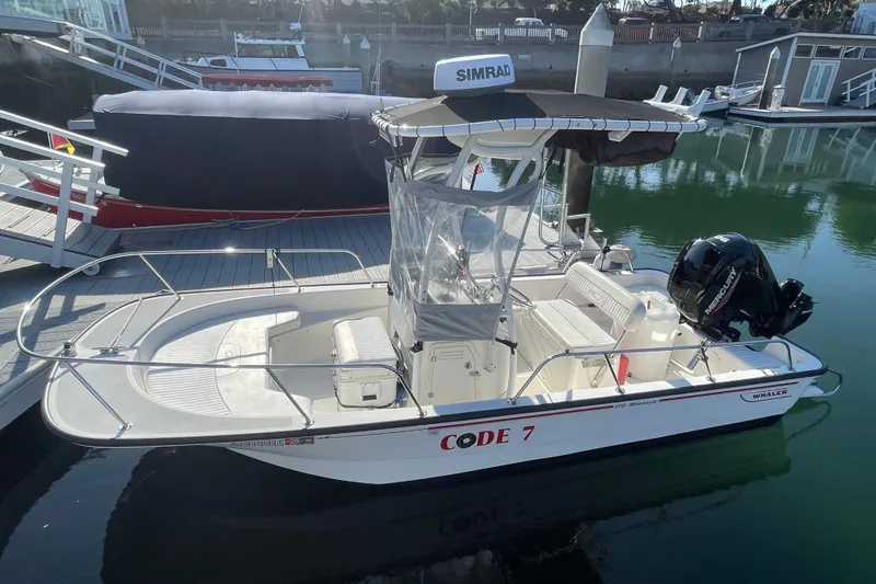 Slide: The Image of 2006 Boston Whaler 170 Montauk boat docked, featuring a Simrad system and Mercury engine. - 2
