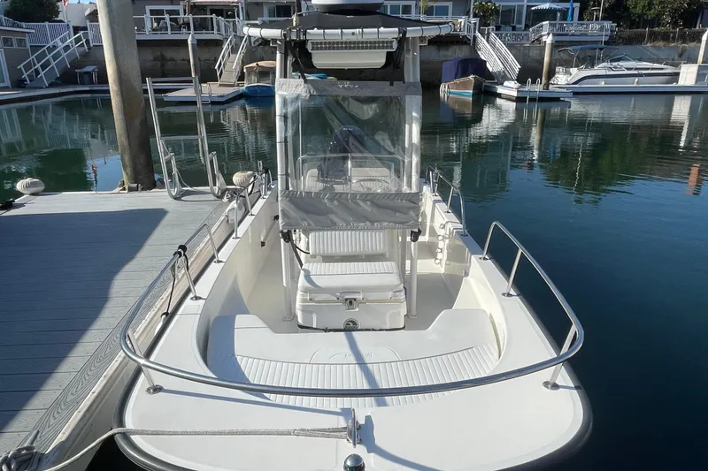 Slide: The Image of 2006 Boston Whaler 170 Montauk boat docked at marina, showcasing spacious deck and seating. - 4