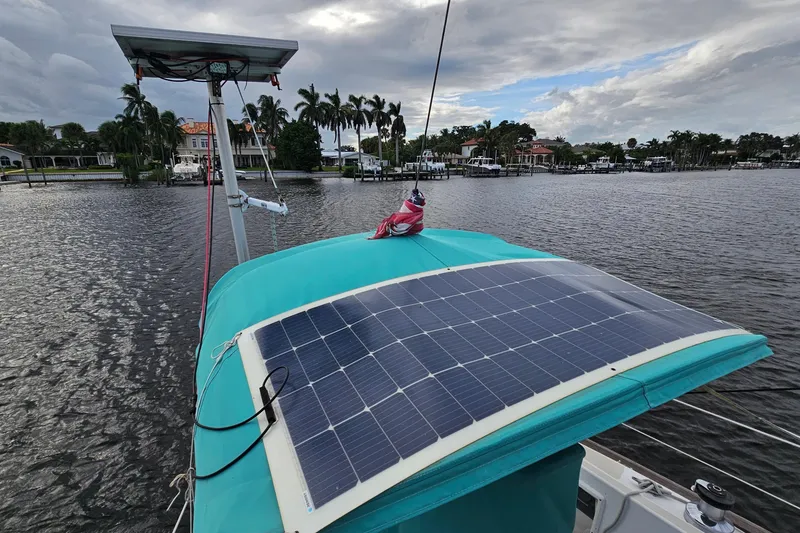 Slide: The Image of 1987 Tartan 37 sailboat with solar panels on deck, docked near waterfront homes. - 23