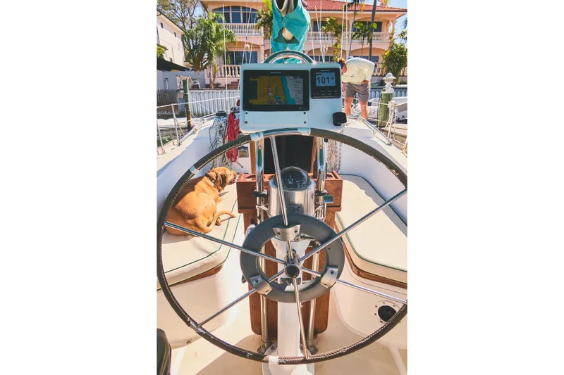 Slide: The Image of Cockpit of 1987 Tartan 37 sailboat with steering wheel, navigation equipment, and a dog lounging. - 3