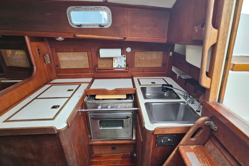 Slide: The Image of 1987 Tartan 37 yacht kitchen with stove, dual sinks, and wooden cabinetry. - 30