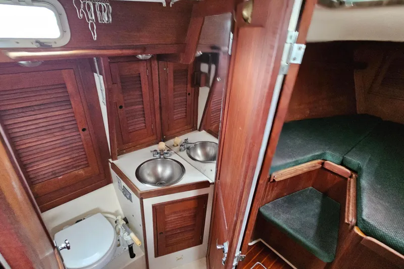 Slide: The Image of 1987 Tartan 37 yacht interior with wooden cabinetry, dual sinks, and cozy sleeping area. - 52