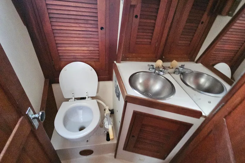 Slide: The Image of 1987 Tartan 37 yacht bathroom with wooden cabinets, toilet, and dual sinks. - 58
