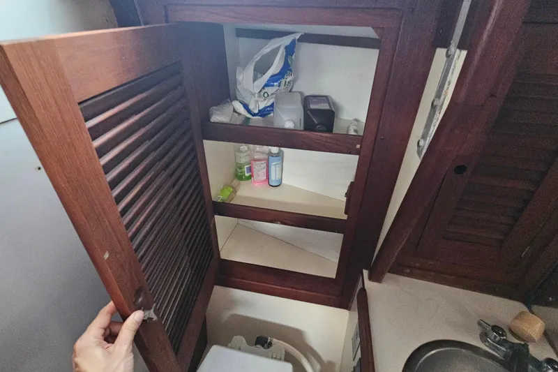 Slide: The Image of Wooden cabinet with toiletries inside a 1987 Tartan 37 sailboat bathroom. - 59