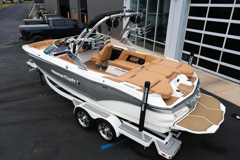 Slide: The Image of 2019 MasterCraft X22 boat with tan seating, parked on a trailer near a building. - 5