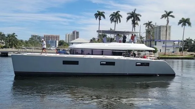 Slide: The Image of 2015 Lagoon Motor Yacht cruising on a sunny day with palm trees and buildings in the background. - 36