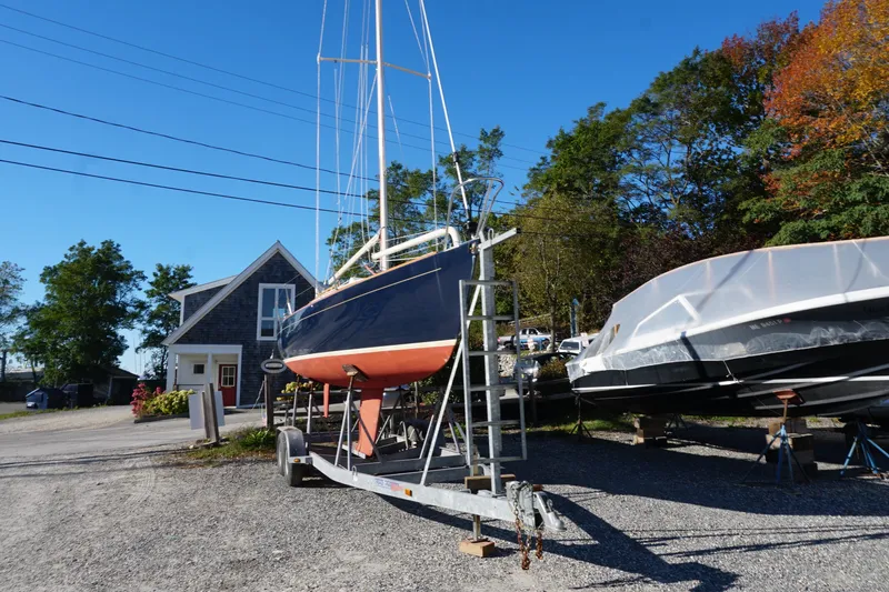 Slide: The Image of Alerion Express 28 sailboat from 2006 on trailer, near a house, under clear blue sky. - 10