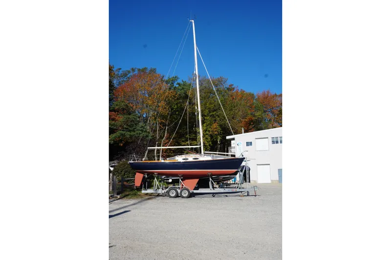 Slide: The Image of 2006 Alerion Express 28 sailboat on trailer, surrounded by autumn trees and a building. - 12