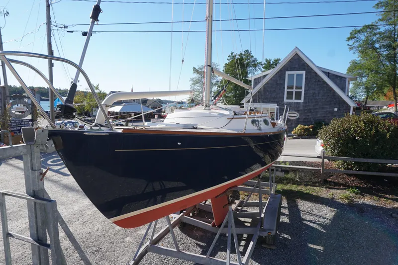 Slide: The Image of 2006 Alerion Express 28 sailboat on trailer, dockside with rustic building background. - 13