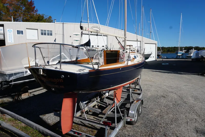 Slide: The Image of 2006 Alerion Express 28 sailboat on trailer, docked near a marina under clear blue sky. - 16