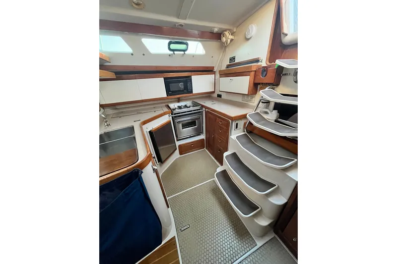 Slide: The Image of 1996 Catalina 400 yacht interior kitchen with stove, sink, and storage cabinets. - 33