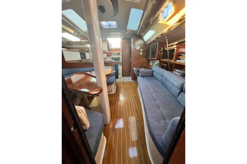 Slide: The Image of Interior of a 1996 Catalina 400 sailboat with blue seating and wooden flooring. - 52