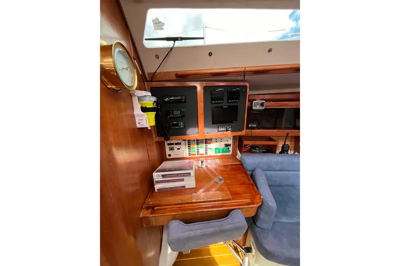 Slide: The Image of Navigation station inside 1996 Catalina 400 sailboat with control panels and seating. - 64