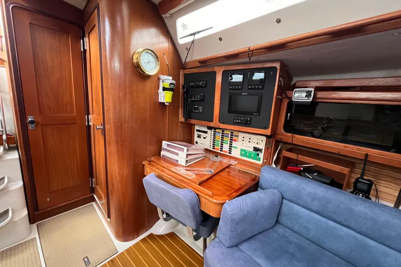 Slide: The Image of Navigation station inside a 1996 Catalina 400 sailboat, featuring wooden cabinetry and control panels. - 70