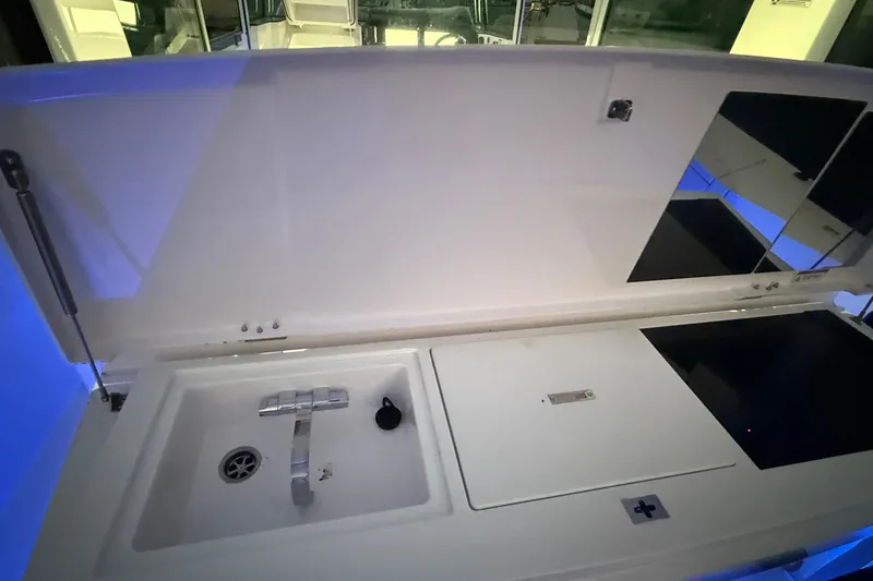 Slide: The Image of 2024 Axopar 37 boat interior with sink and countertop, illuminated by blue lighting. - 17