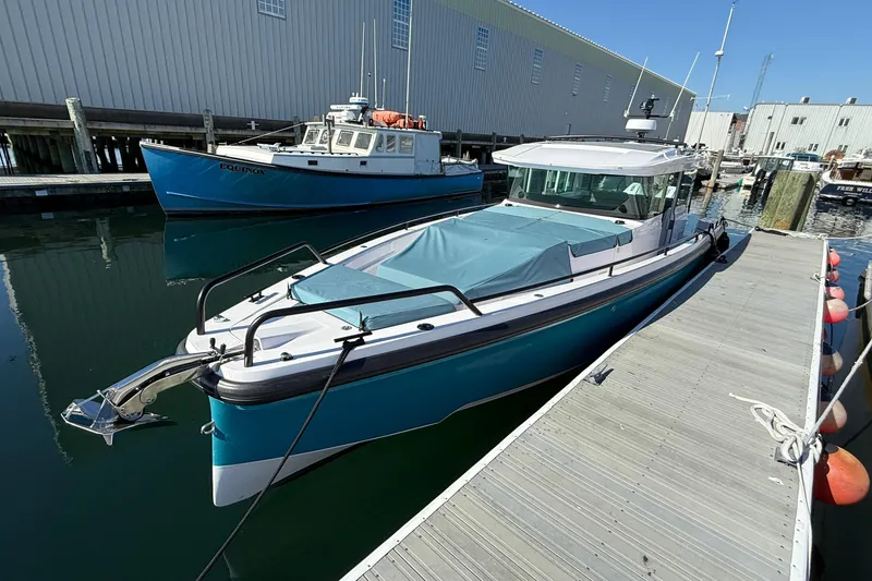 Slide: The Image of 2024 Axopar 37 boat docked at marina, featuring sleek design and blue cover. - 19