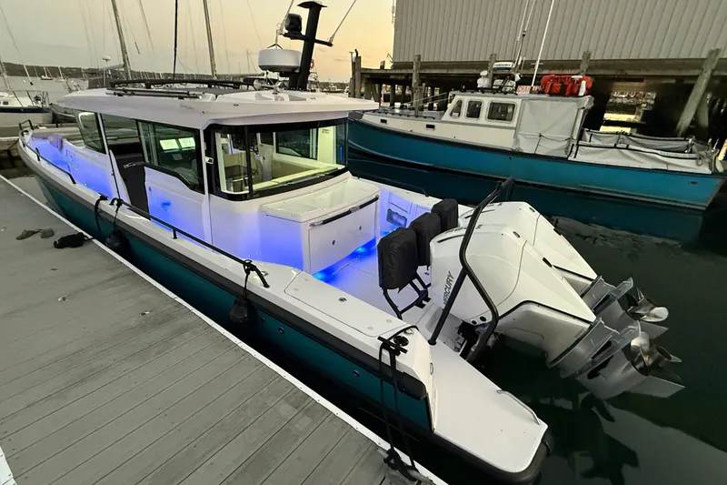 Slide: The Image of 2024 Axopar 37 boat docked, featuring modern design and illuminated interior. - 2