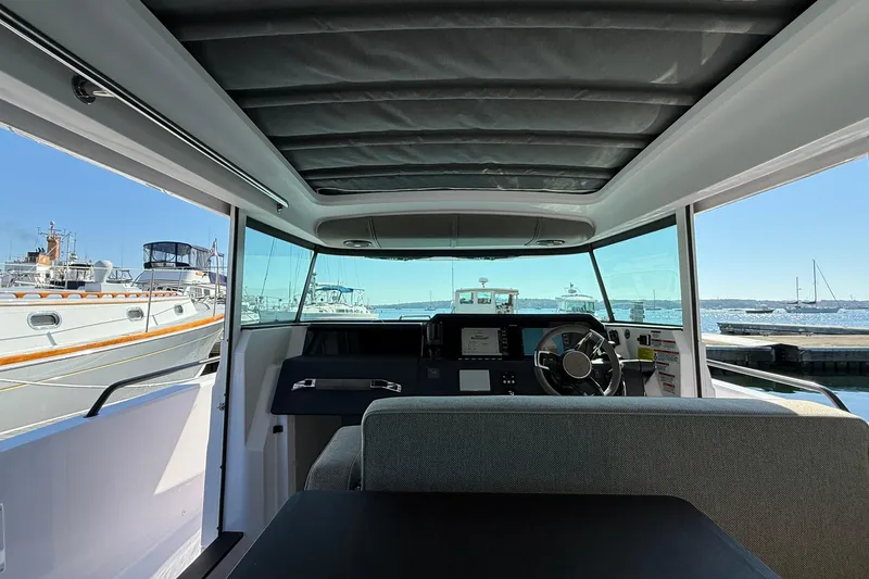 Slide: The Image of Interior view of 2024 Axopar 37 boat, showcasing helm and seating area at marina. - 21