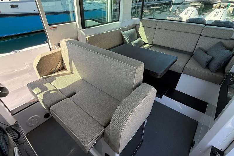 Slide: The Image of 2024 Axopar 37 interior with gray seating and table, docked at marina. - 25