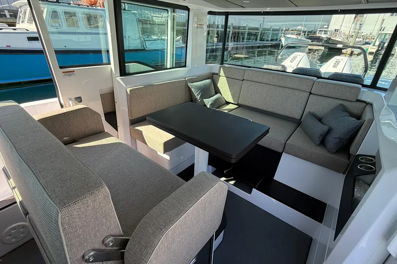 Slide: The Image of 2024 Axopar 37 interior with gray seating, table, and waterfront view. - 26