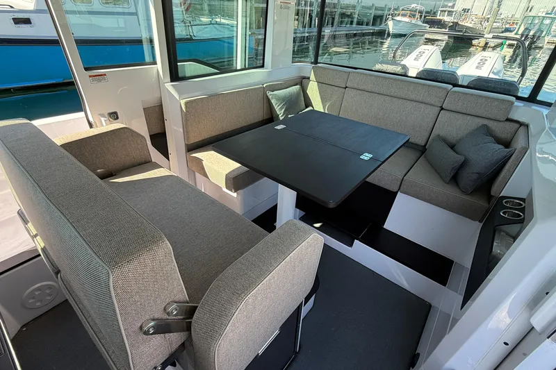 Slide: The Image of 2024 Axopar 37 interior with gray seating, table, and marina view. - 27
