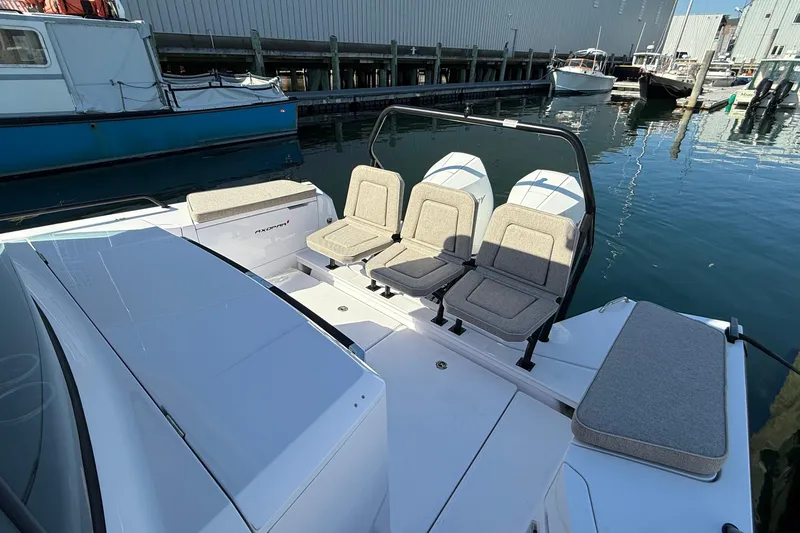 Slide: The Image of 2024 Axopar 37 boat with cushioned seating, docked in a marina. - 32