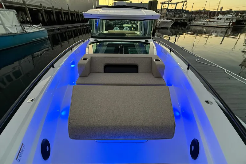 Slide: The Image of 2024 Axopar 37 boat with illuminated deck and cushioned seating at sunset. - 4