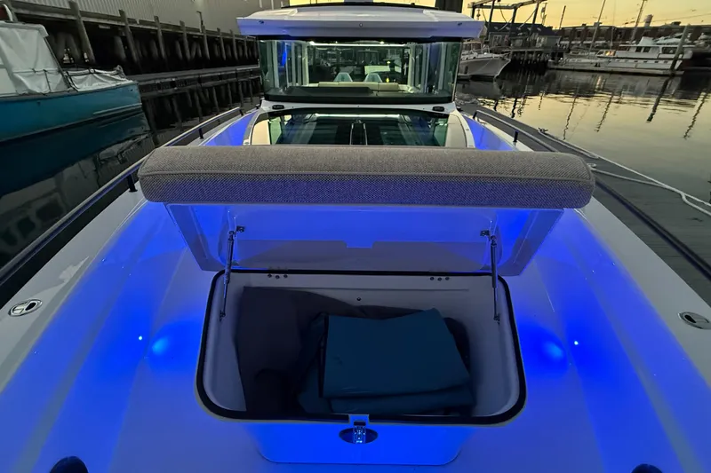 Slide: The Image of 2024 Axopar 37 boat with open storage compartment, illuminated by blue lights at a marina. - 6