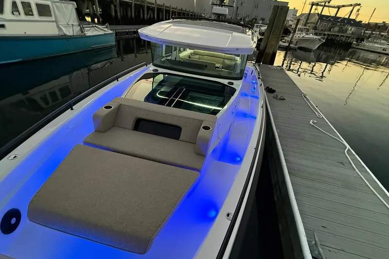 Slide: The Image of 2024 Axopar 37 boat docked, featuring blue LED lights and a spacious deck. - 8
