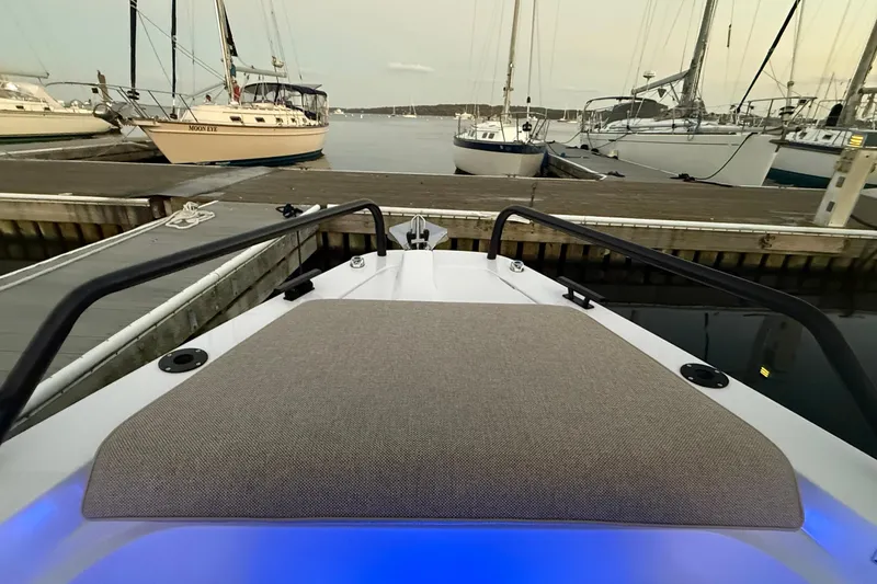 Slide: The Image of 2024 Axopar 37 boat docked, featuring a cushioned bow area with surrounding sailboats. - 9