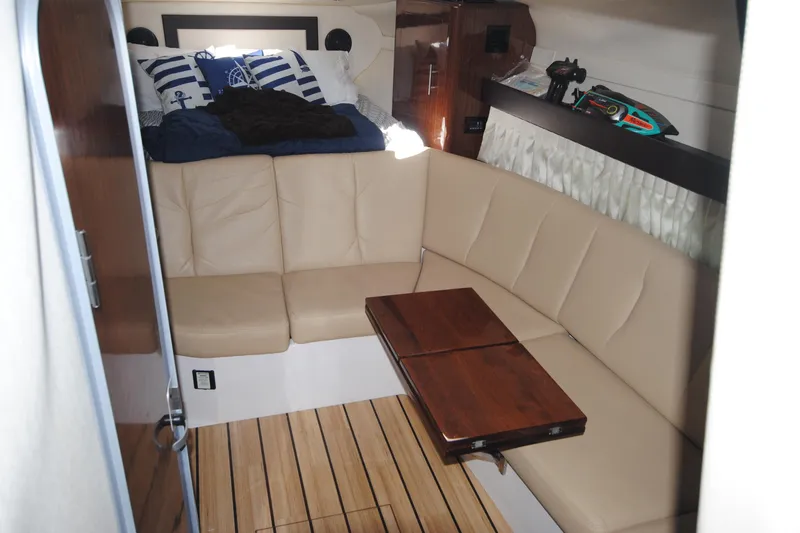 Slide: The Image of 2015 Regal 32 Express cabin with beige seating, wooden table, and nautical decor. - 14