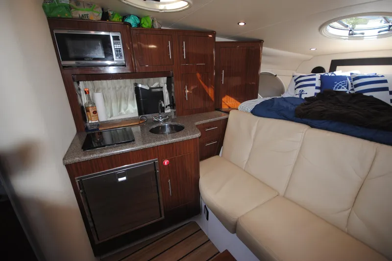 Slide: The Image of 2015 Regal 32 Express cabin interior with kitchenette, microwave, sink, and cozy seating area. - 17
