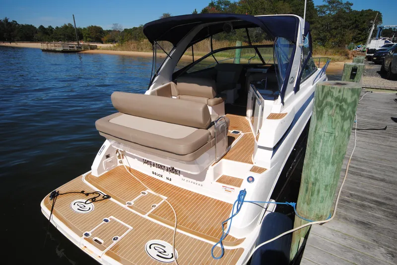 Slide: The Image of 2015 Regal 32 Express boat docked, featuring spacious deck and seating area. - 3